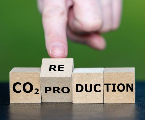 Wooden blocks spelling “CO₂ production” with a block labelled “RE” being placed on top to form “CO₂ reduction”.